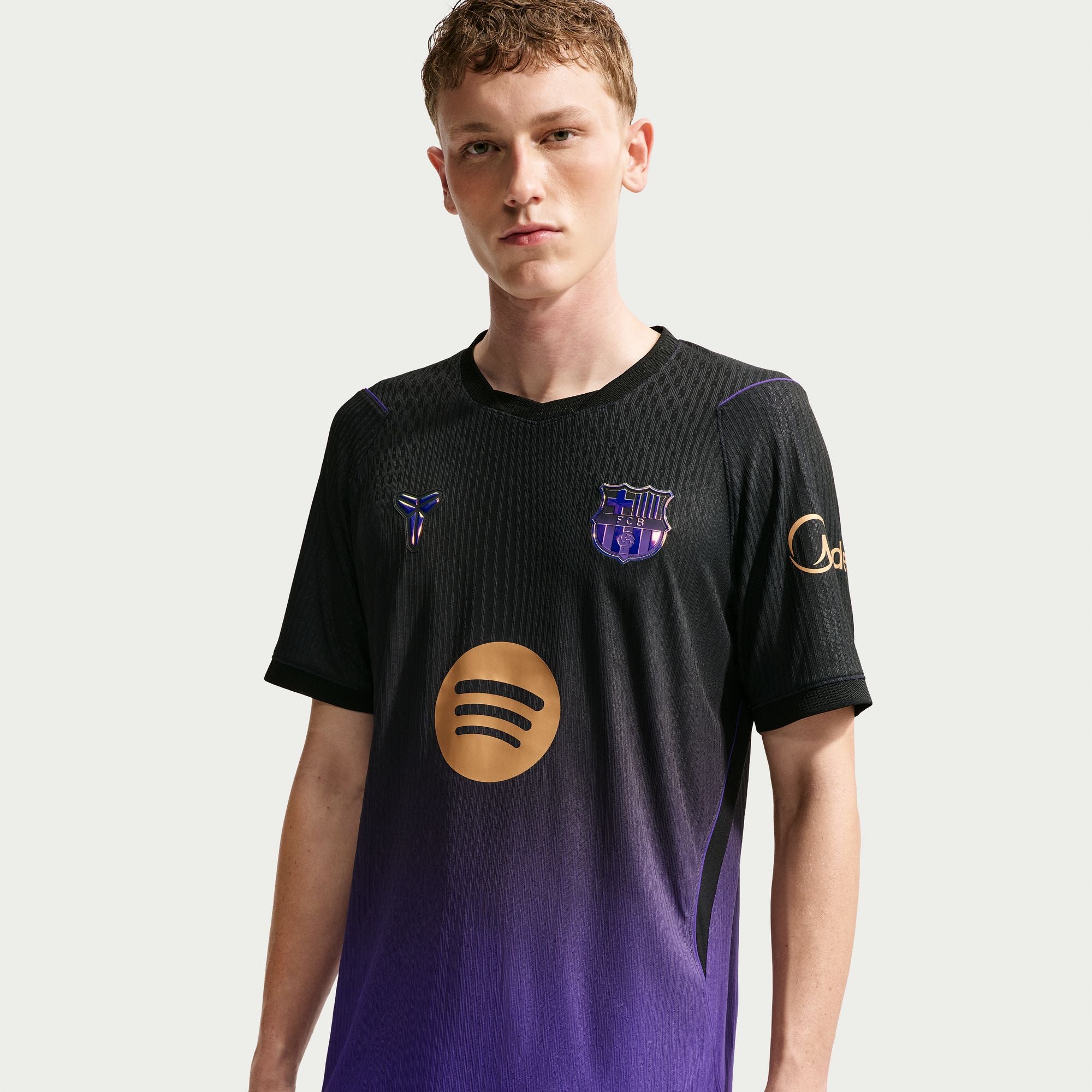 Person wearing a black and purple sports jersey with logos on a white background