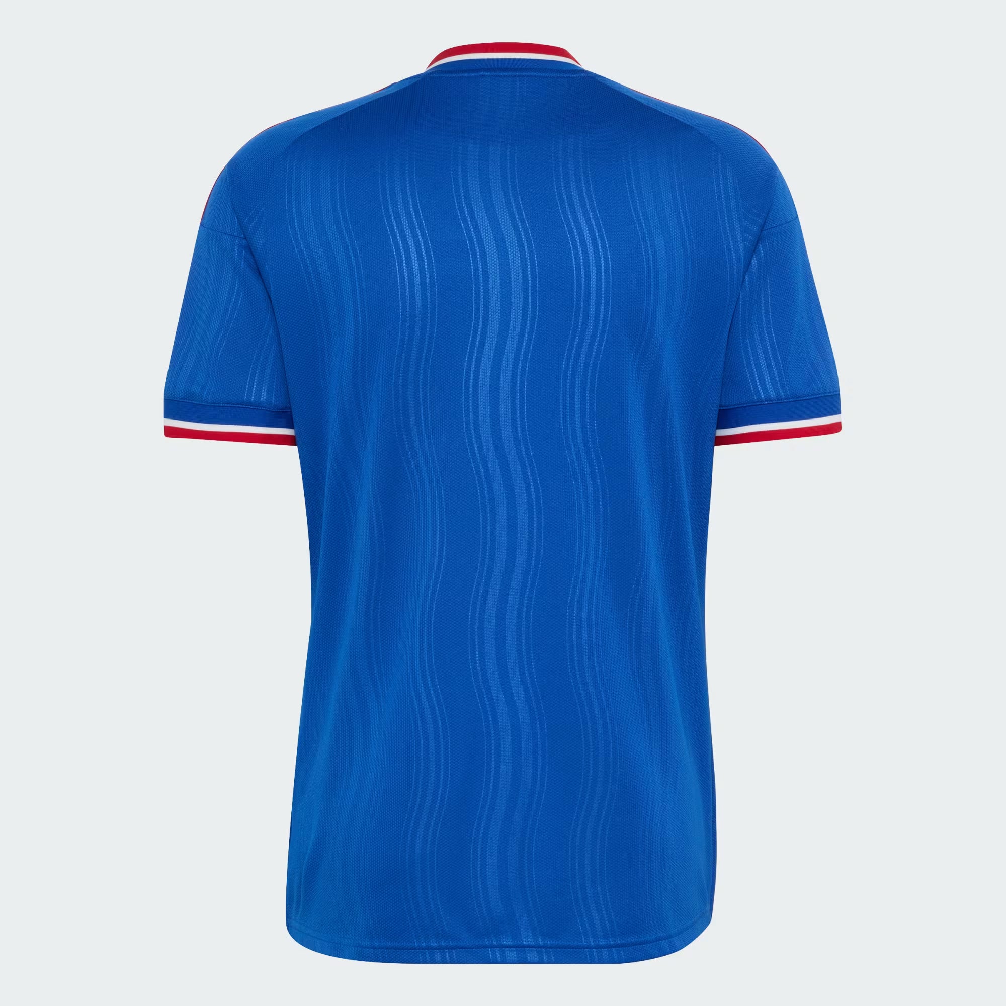A royal blue short-sleeve soccer jersey shown from the back, featuring a subtle vertical wavy texture and red and white trim at the collar and sleeve cuffs, set against a light gray background.