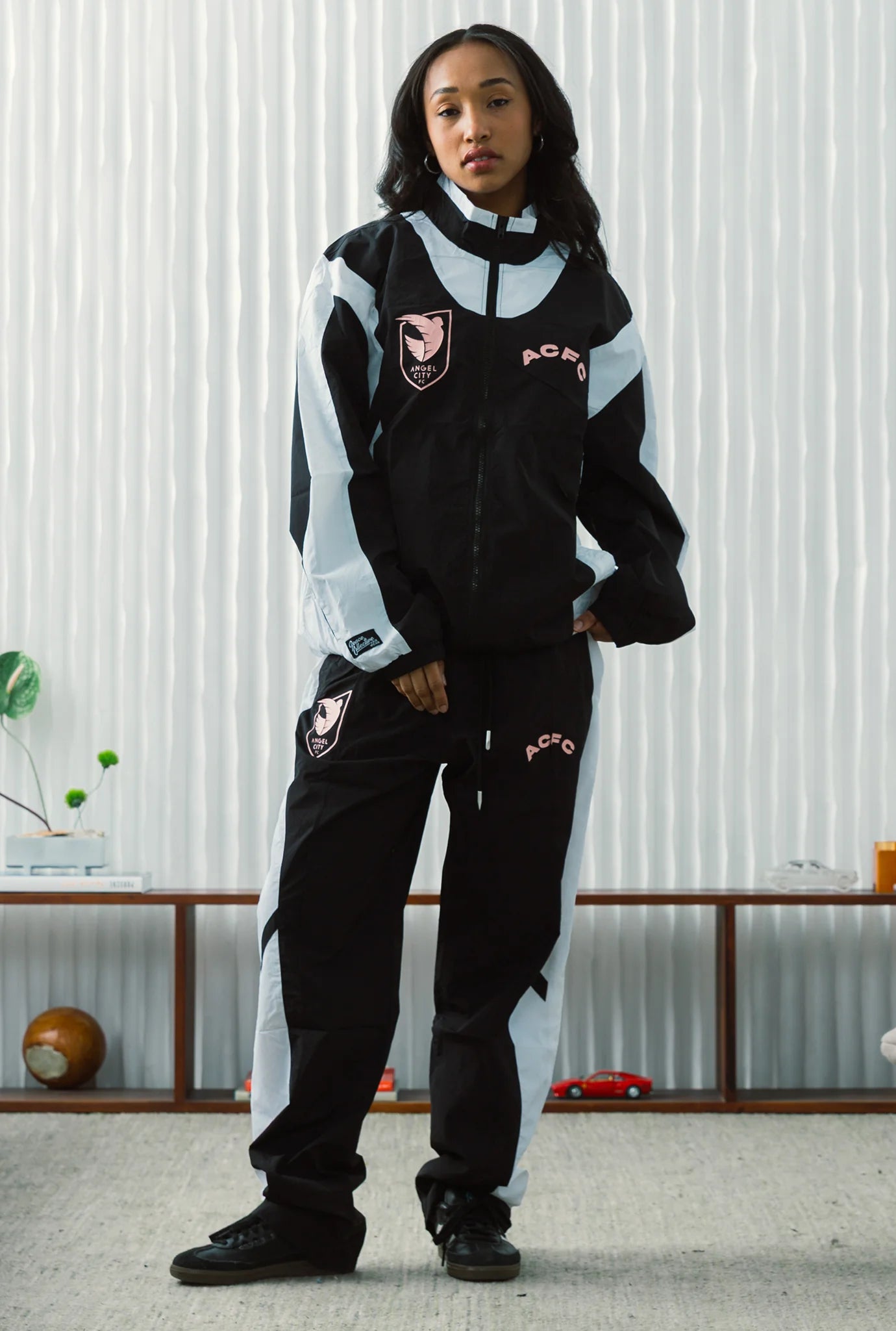 Person wearing a black and white tracksuit with visible branding in an indoor setting.